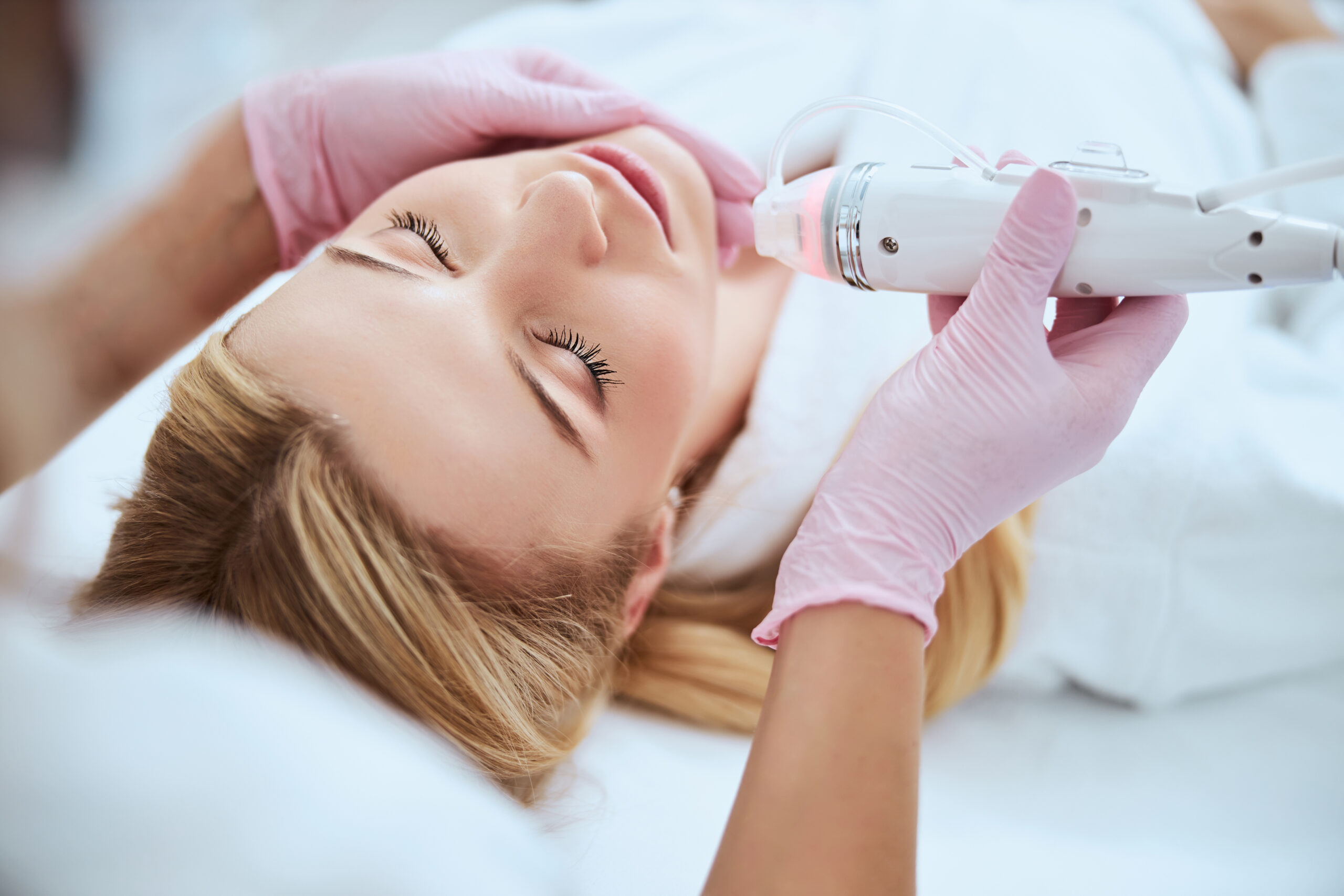 Serene woman receiving fractional microneedling treatment in a beauty salon.
